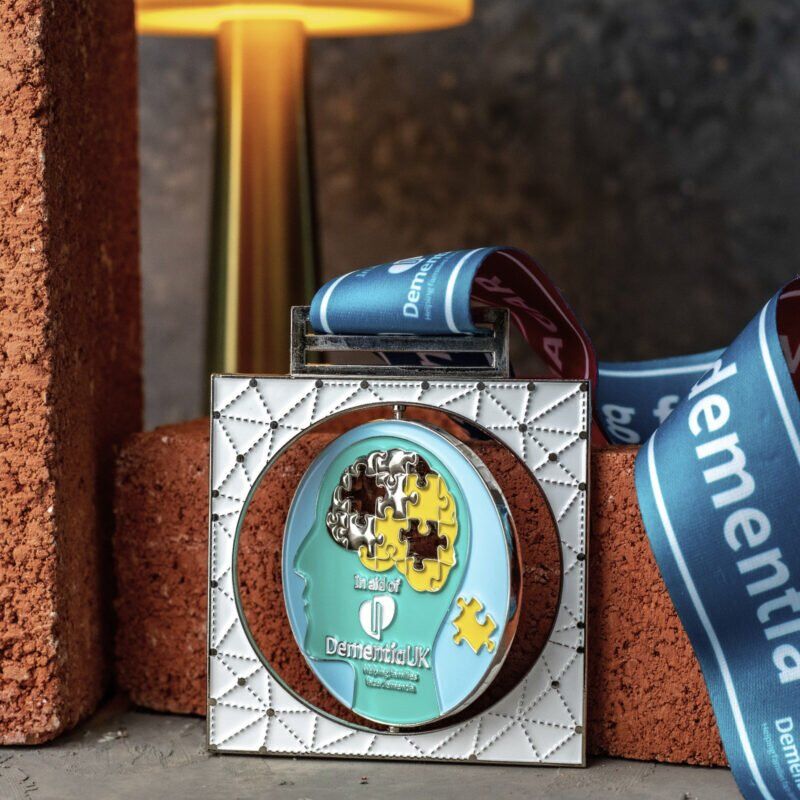 Dementia UK medal with puzzle design and warm backdrop