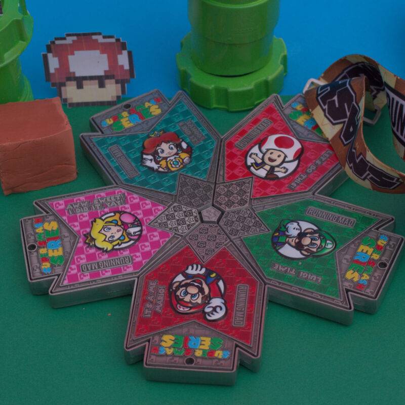 Assortment of colorful Super Smash Series medals with video game character designs.