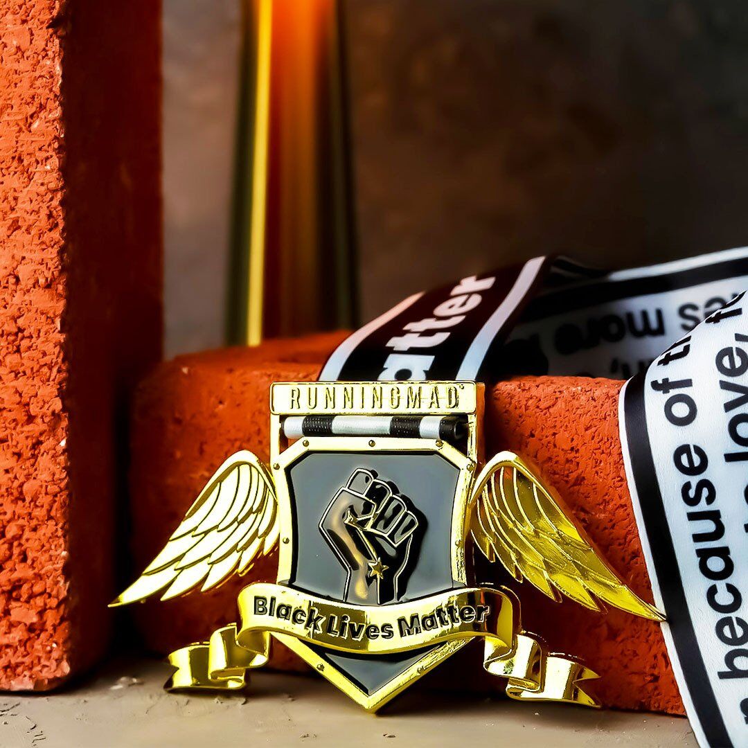 Golden-winged Black Lives Matter medal on grassy field.